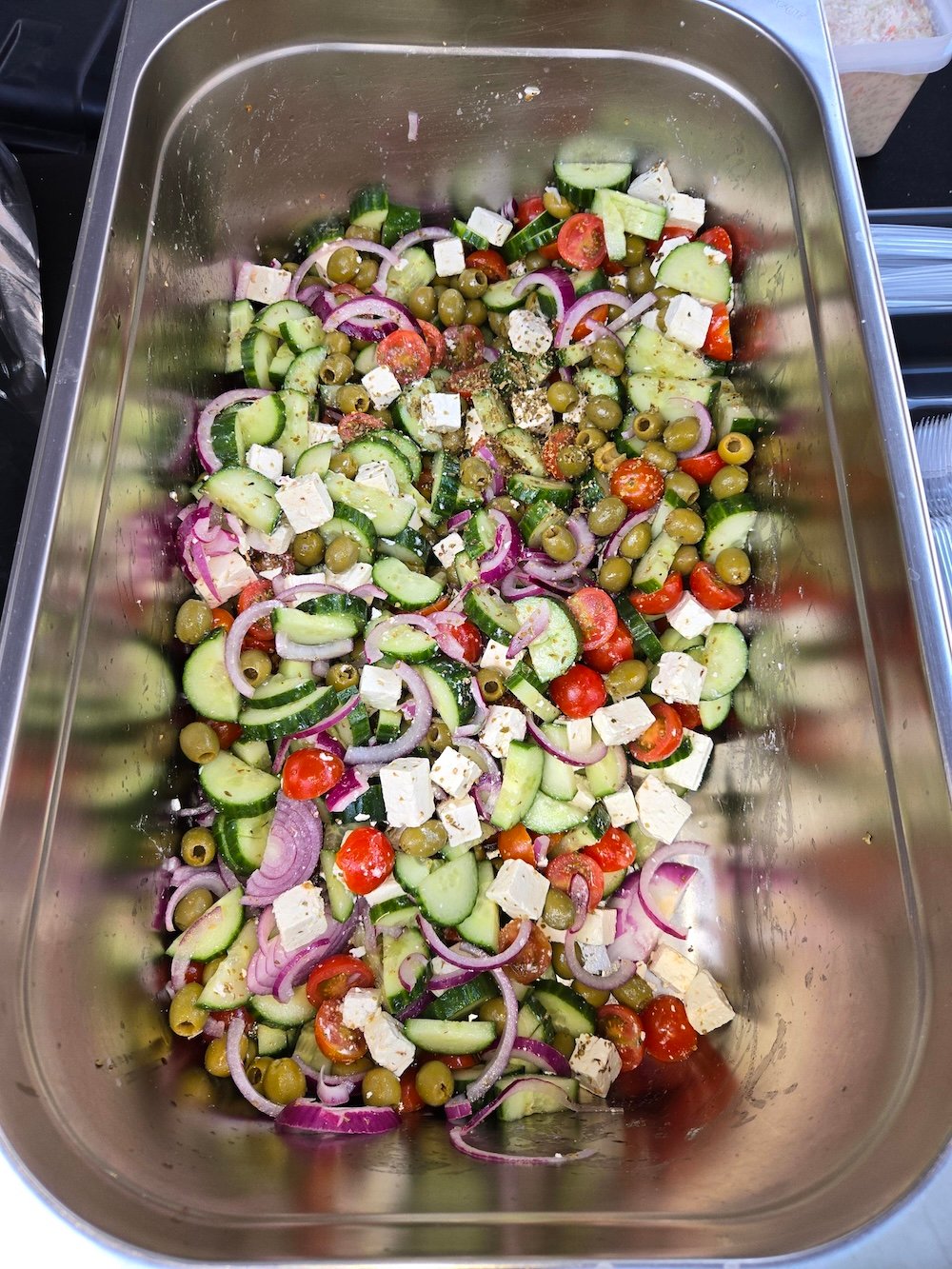 Greek salad with cucumber, tomatoes, olives, red onion and feta in a catering tray